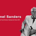 Colonel Sanders in his signature white suit holding a bucket of fried chicken